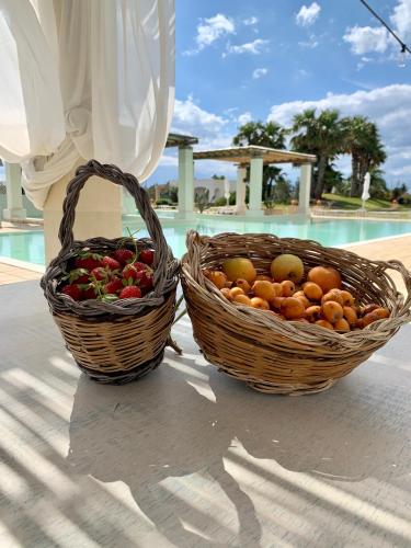 Dos cestas de fruta junto a una piscina. en Borgo Rosso Terra, en Gallipoli