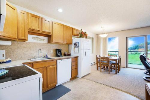 a kitchen with white appliances and a dining room with a table at Sandpiper Condo in Moclips