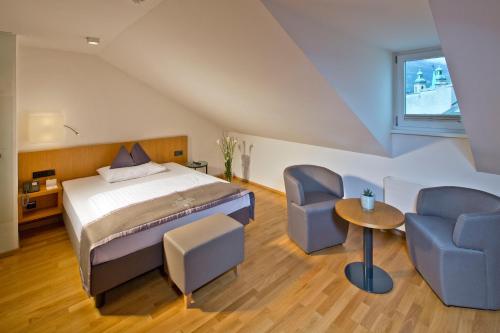 a room with a bed, chair, and a desk at Hotel Maximilian - Stadthaus Penz in Innsbruck