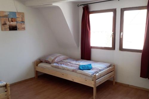 a small bed in a room with two windows at Workers House mit 7 Zimmern, Terrasse und Balkon 