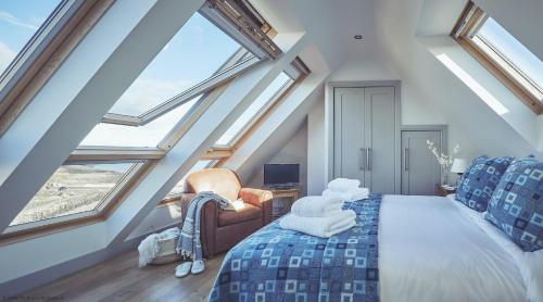a attic bedroom with a bed and large windows at Craster Reach in Craster