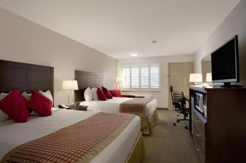 a hotel room with two beds and a flat screen tv at Ramada by Wyndham Tempe/At Arizona Mills Mall in Tempe