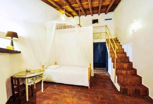 a bedroom with a bed and a staircase with a table at Casa do Castelo - Zona Histórica in Mértola