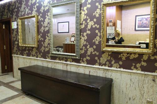 a woman in a bathroom with two mirrors at Hotel El Castillo in Ponferrada