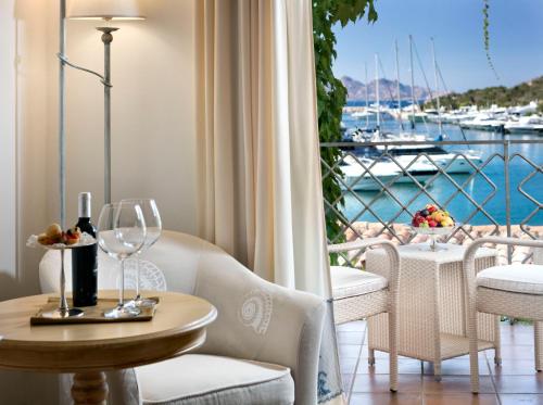 a dining room table with chairs and a glass of wine at Grand Hotel Poltu Quatu in Porto Cervo