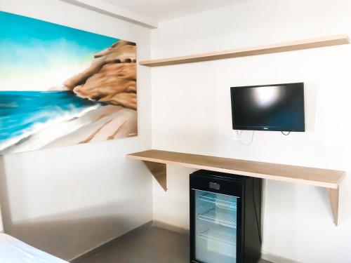Habitación con TV en la pared con una foto en Pousada La Acolhida, en Cabo Frío
