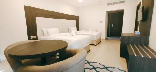 ein Hotelzimmer mit 2 Betten und einem Tisch in der Unterkunft Manazil Aldar Hotel in Suhar