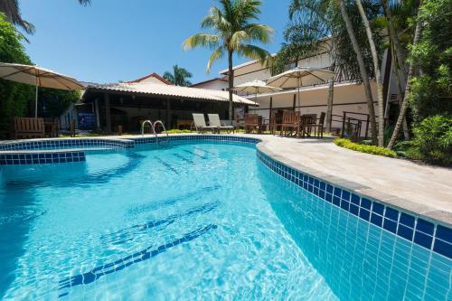 a swimming pool in a resort with palm trees at Hotel Ilhas da Grécia in Guarujá