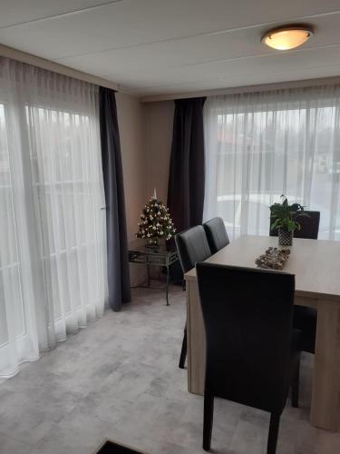 a living room with a table and chairs and windows at krabbenkreek 2 in Sint Annaland