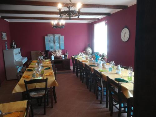 Agriturismo Polla في Camporgiano: غرفة طعام بطاولات وكراسي طويلة وساعة