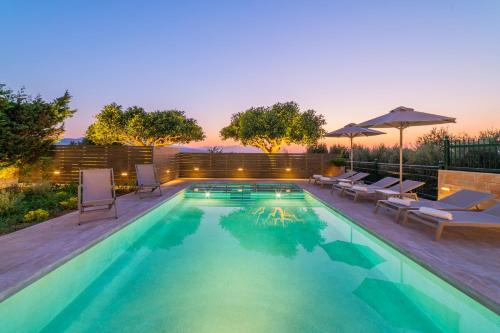 una piscina con sillas y sombrillas en Estella Villa with Pool, Children Area, BBQ & Magnificent Views!, en Astérion