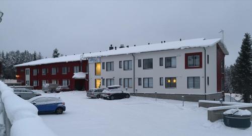 un edificio cubierto de nieve con coches aparcados en un aparcamiento en Levi Ski-Star 220, en Levi