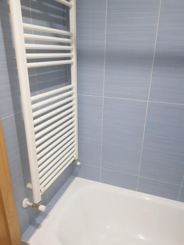 Baño de azulejos azules con radiador blanco en Apartamentos Burela, en Burela de Cabo