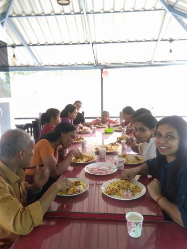 a group of people sitting at a table eating pizza at Taj Mahal Hotel in Cochin