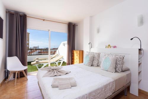 1 dormitorio con cama blanca y balcón en Home2Book Paradise Costa Adeje, Pool, en Playa Fañabe