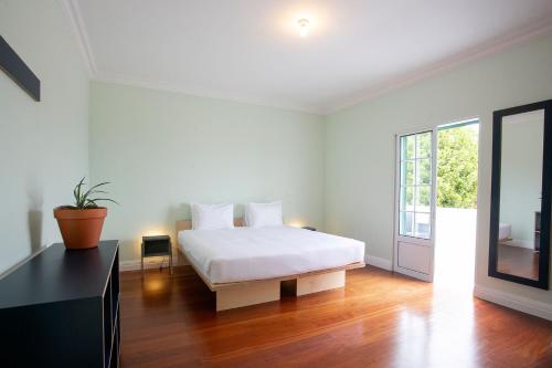 a white bedroom with a bed and a window at Salt Lips Surf & Coworking Azores in Ponta Delgada