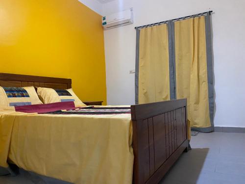 a bedroom with a bed and a yellow wall at Gîte Le Toubé in Saint-Louis