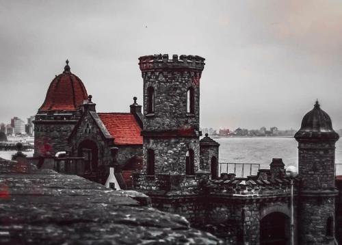 an old stone building with a red roof next to the water at Hotel Artico in Mar del Plata
