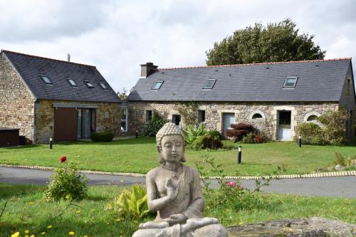 Una statua seduta sull'erba di fronte a una casa di Keryanti Domaine de Lesleac'h a Plouégat-Moysan