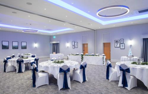 a banquet hall with white tables and blue chairs at Sedgebrook Hall in Northampton
