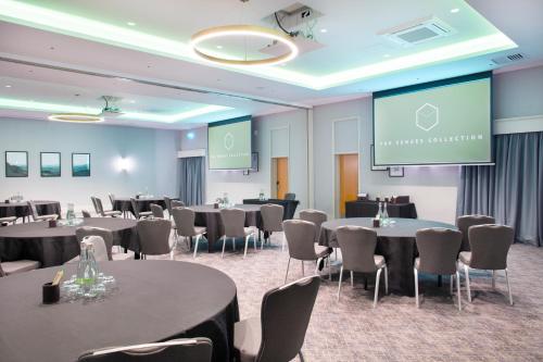 a conference room with tables and chairs and a screen at Sedgebrook Hall in Northampton