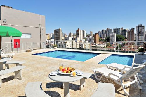 - une terrasse avec une table et une piscine dans un bâtiment dans l'établissement Hotel Nacional Inn Ribeirão Preto, à Ribeirão Preto