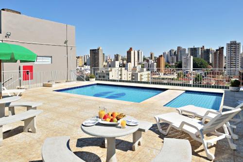 un patio con una mesa y una piscina en un edificio en Hotel Nacional Inn Ribeirão Preto, en Ribeirão Preto