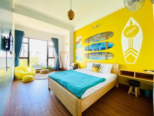 a bedroom with a bed and a yellow wall at Blossom Sea Homestay Quy Nhơn in Quy Nhon