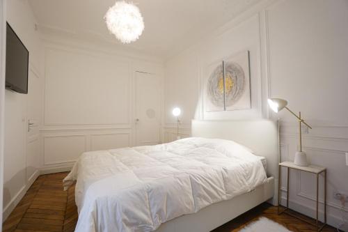 a white bedroom with a bed and a chandelier at Modern Duplex Close To The Eiffel Tower in Paris