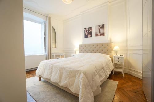 une chambre blanche avec un grand lit et une fenêtre dans l'établissement Modern Duplex Close To The Eiffel Tower, à Paris