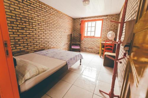 a bedroom with a bed and a window at Chalés Caminhos Do Rosa in Praia do Rosa