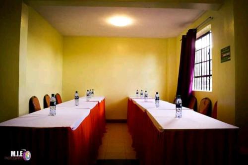 una fila de mesas en una habitación con paredes rojas y amarillas en Crown Hotel Kericho, en Kericho