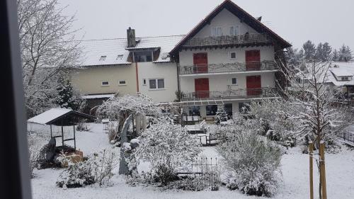 a house with snow on the ground in front of it at Hotel KAMPS in Sinsheim
