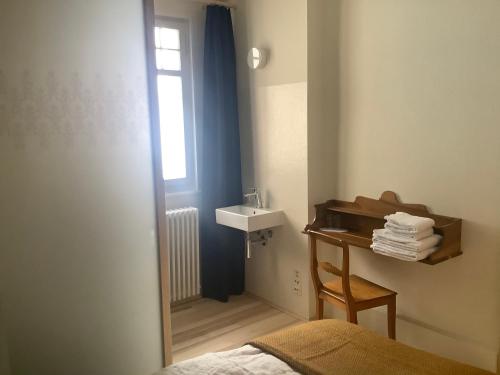 a bathroom with a sink and a bed and a table at Hotel Erica in Langenbruck