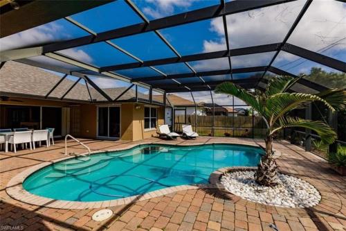 a large swimming pool with a retractable roof at Tiki Paradise House & pool - 10 min to Beach! in Bonita Springs