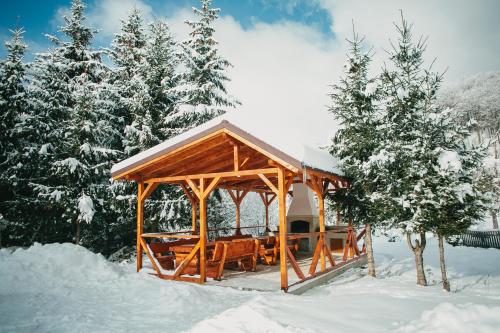 a wooden gazebo in the snow with trees at Chalet 2B in Cavnic