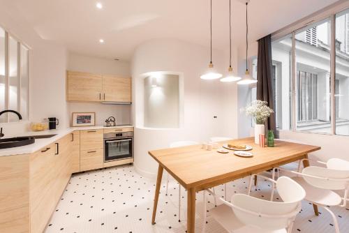 - une cuisine avec une table en bois et des chaises blanches dans l'établissement Central and renovated Parisian apartment, 6-7 guests, à Paris