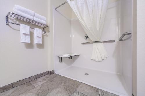 Un baño con toallas blancas y ducha. en Cobblestone Inn & Suites - Holdrege, en Holdrege