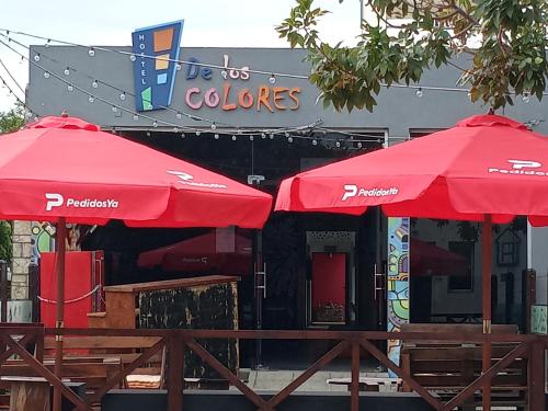 two red umbrellas in front of a restaurant at Hostel de los Colores in Piriápolis
