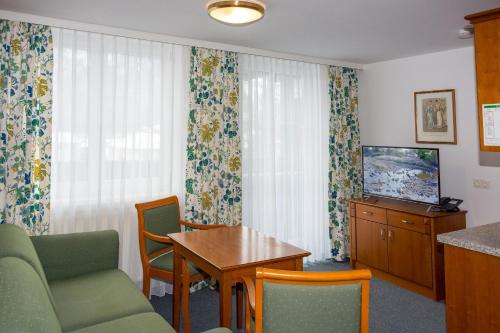 a living room with a couch and a table and a television at Landhotel Post Ebensee am Traunsee ***S in Ebensee