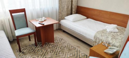 a hotel room with a bed and a table and chair at Hotel Polonia in Rzeszów