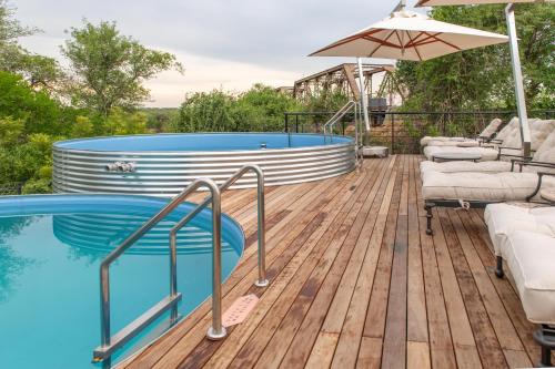 a deck with a swimming pool and an umbrella at Kruger Shalati - Train on The Bridge & Garden Suites in Skukuza