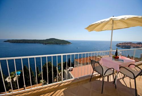 a balcony with a table and an umbrella and the ocean at Sipa Apartments in Dubrovnik