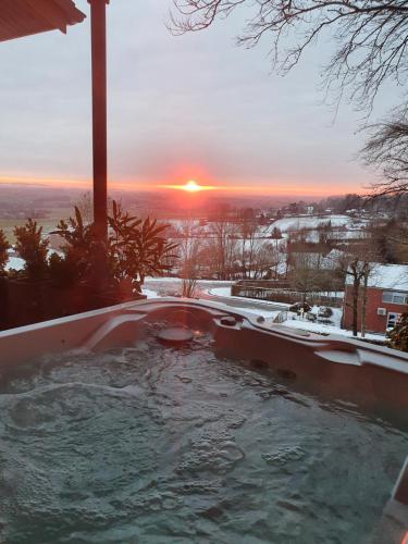 a hot tub with the sunset in the background at Chalet de la Sablière in Amougies
