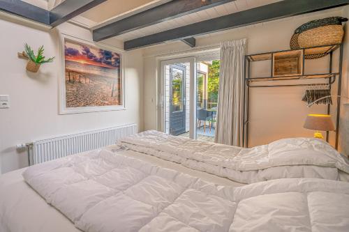 a large white bed in a room with a window at Zee van Tijd in De Koog