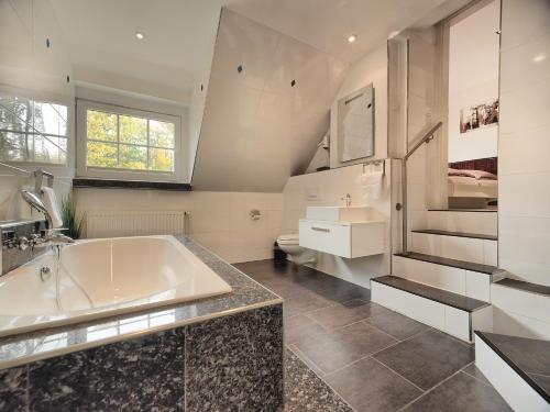ein Badezimmer mit einer Badewanne und einem Waschbecken in der Unterkunft Parkhotel Wienburg Münster in Münster