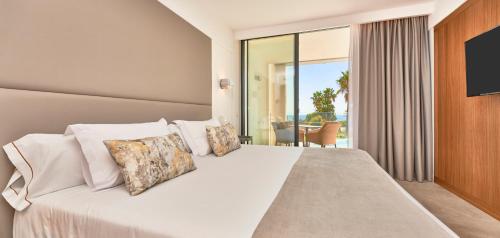 a bedroom with a large white bed with a balcony at Insotel Punta Prima Prestige Suites & Spa in Punta Prima