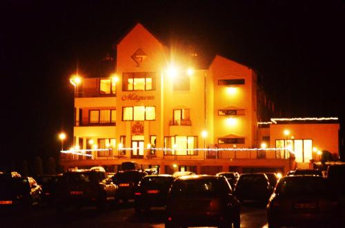 a building with cars parked in a parking lot at night at Pensiunea Magura in Baia Mare