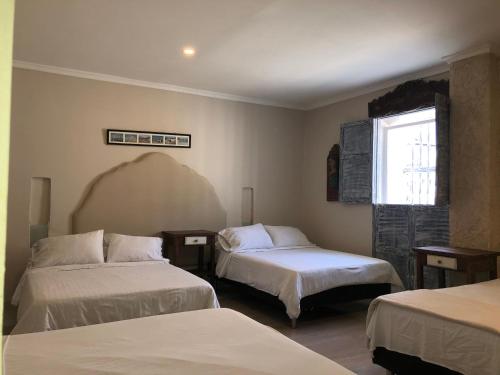 1 dormitorio con 2 camas y ventana en Hotel Galeria la Trinidad en Cartagena de Indias