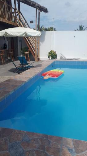 a swimming pool with an umbrella and a red raft at Hostal Villa Brisa in Ballenita